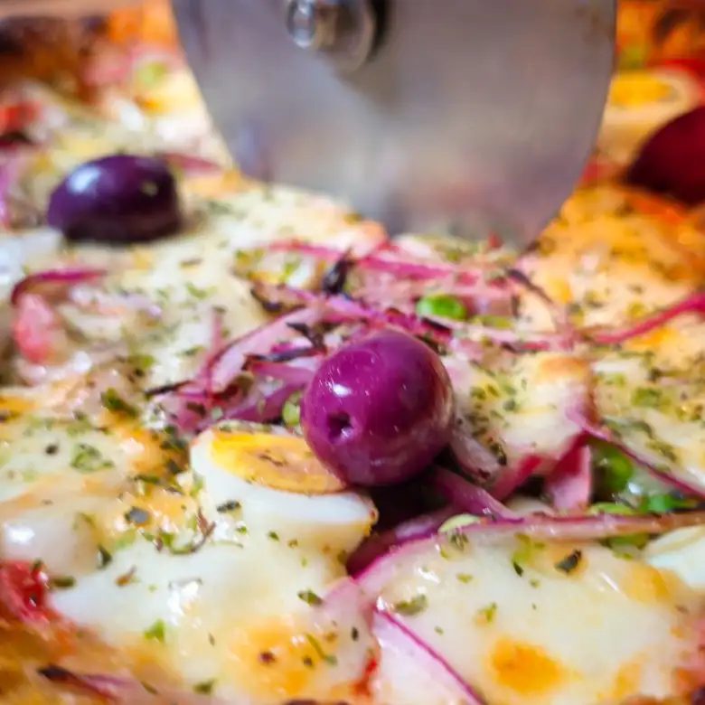 Detalhe do queijo derretido e azeitona da pizza DOVA